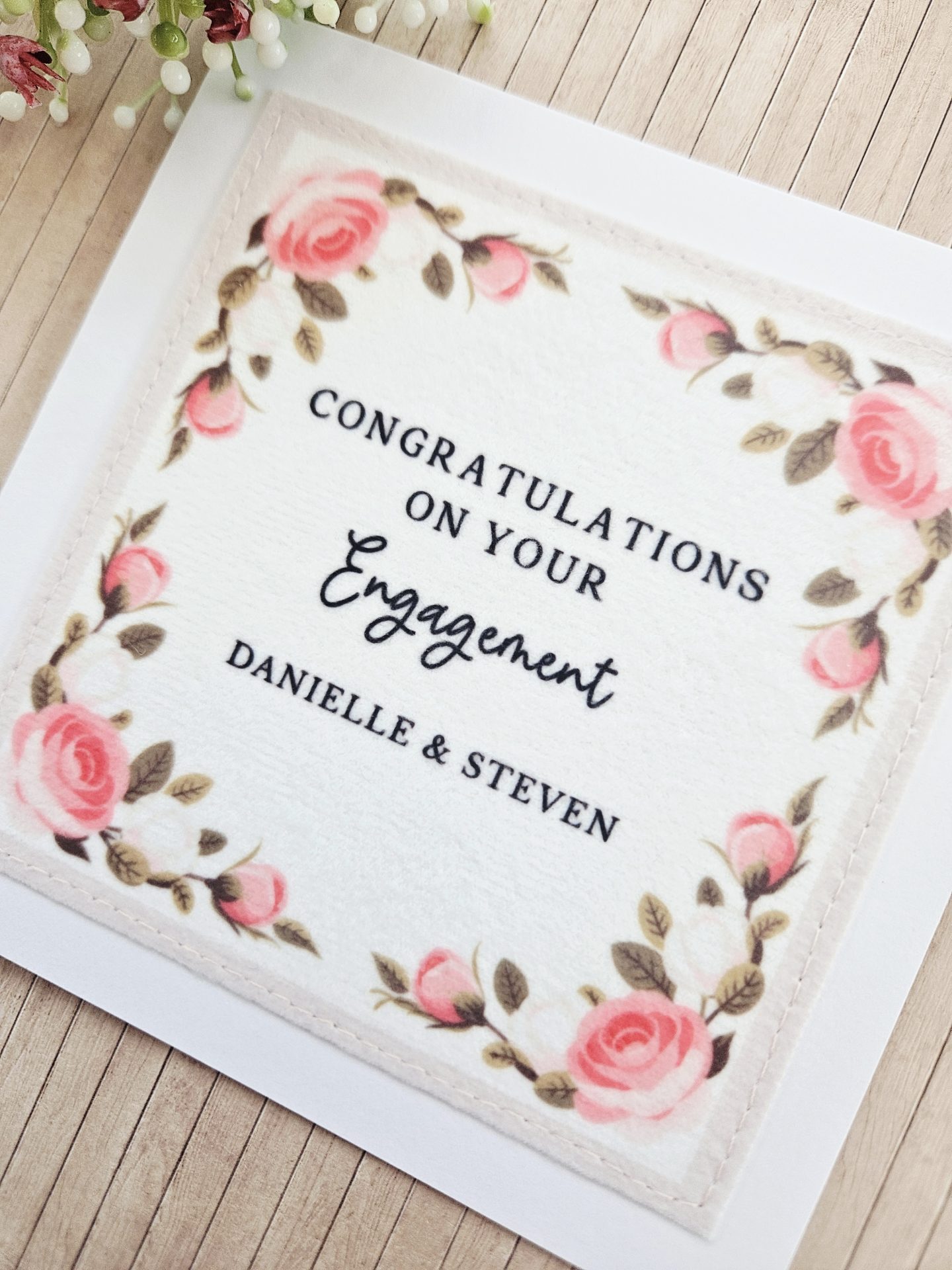 Close up of floral wreath fabric engagement card with stitched edging