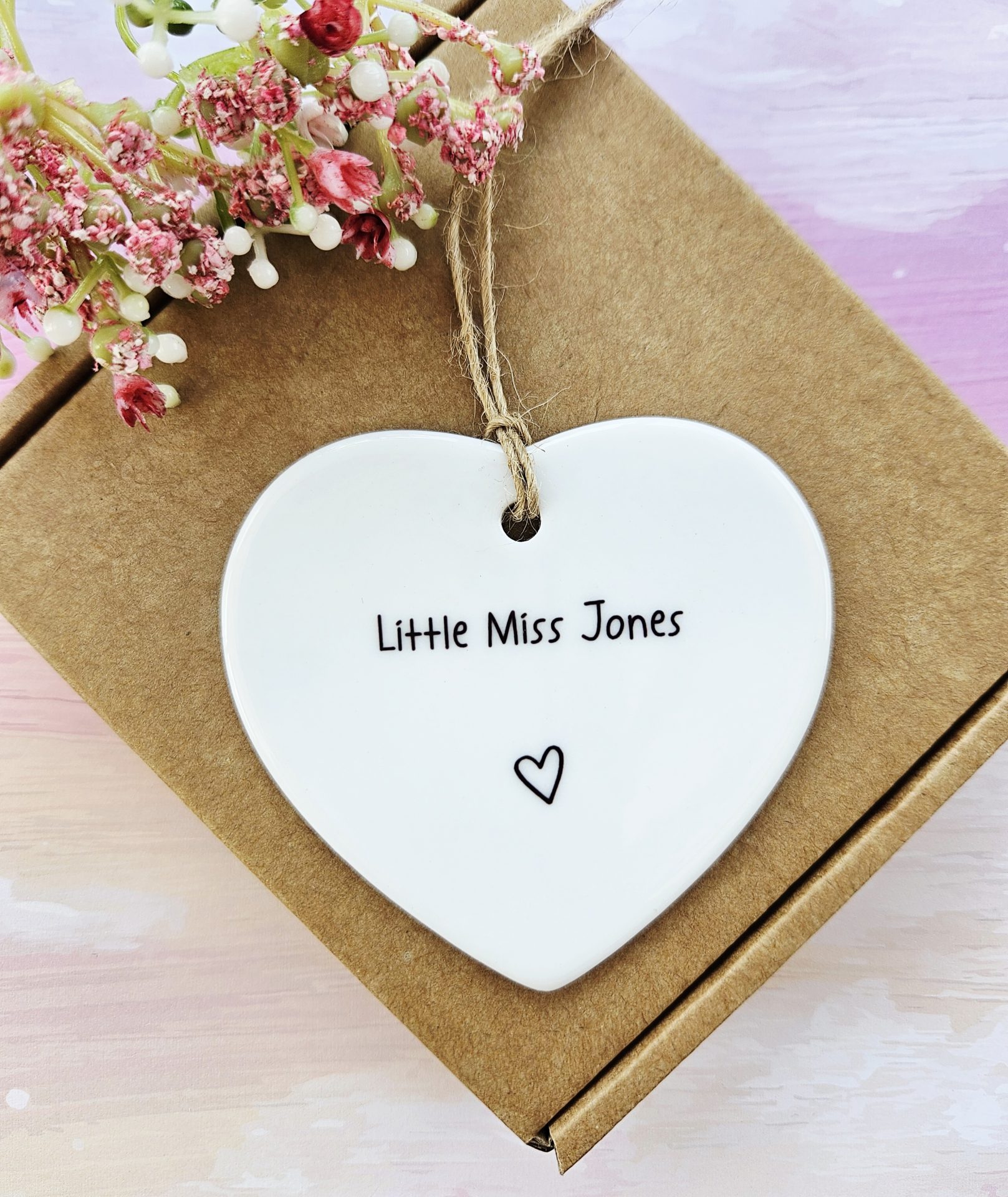 personalised new baby girl ceramic heart keepsake with name hanging on gift box