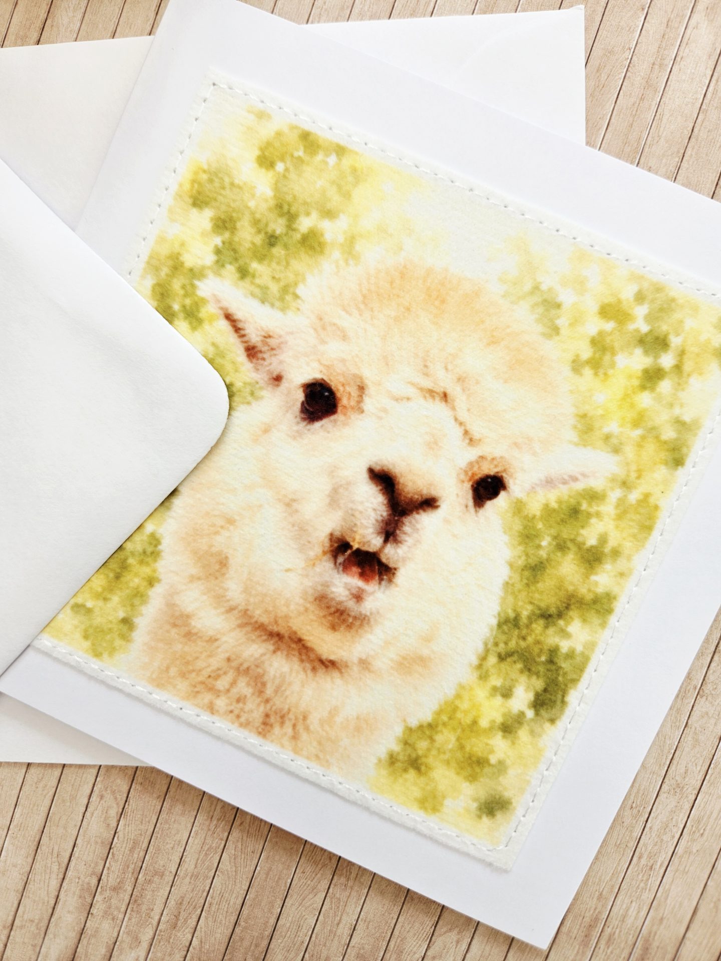 Close up view showing the detailed machine stitching on the fabric panel of a handmade alpaca wildlife greeting card.