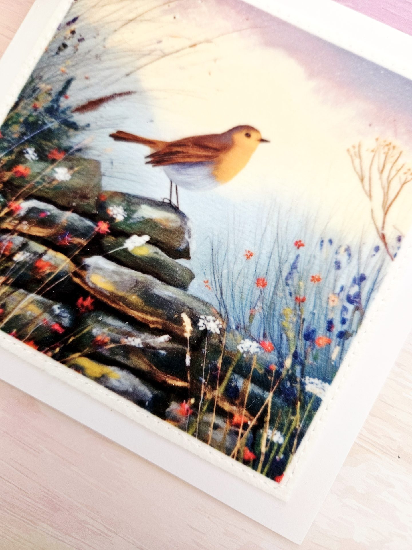 Close up showing the detailed machine stitching on the fabric panel of a handmade robin wildlife greeting card.