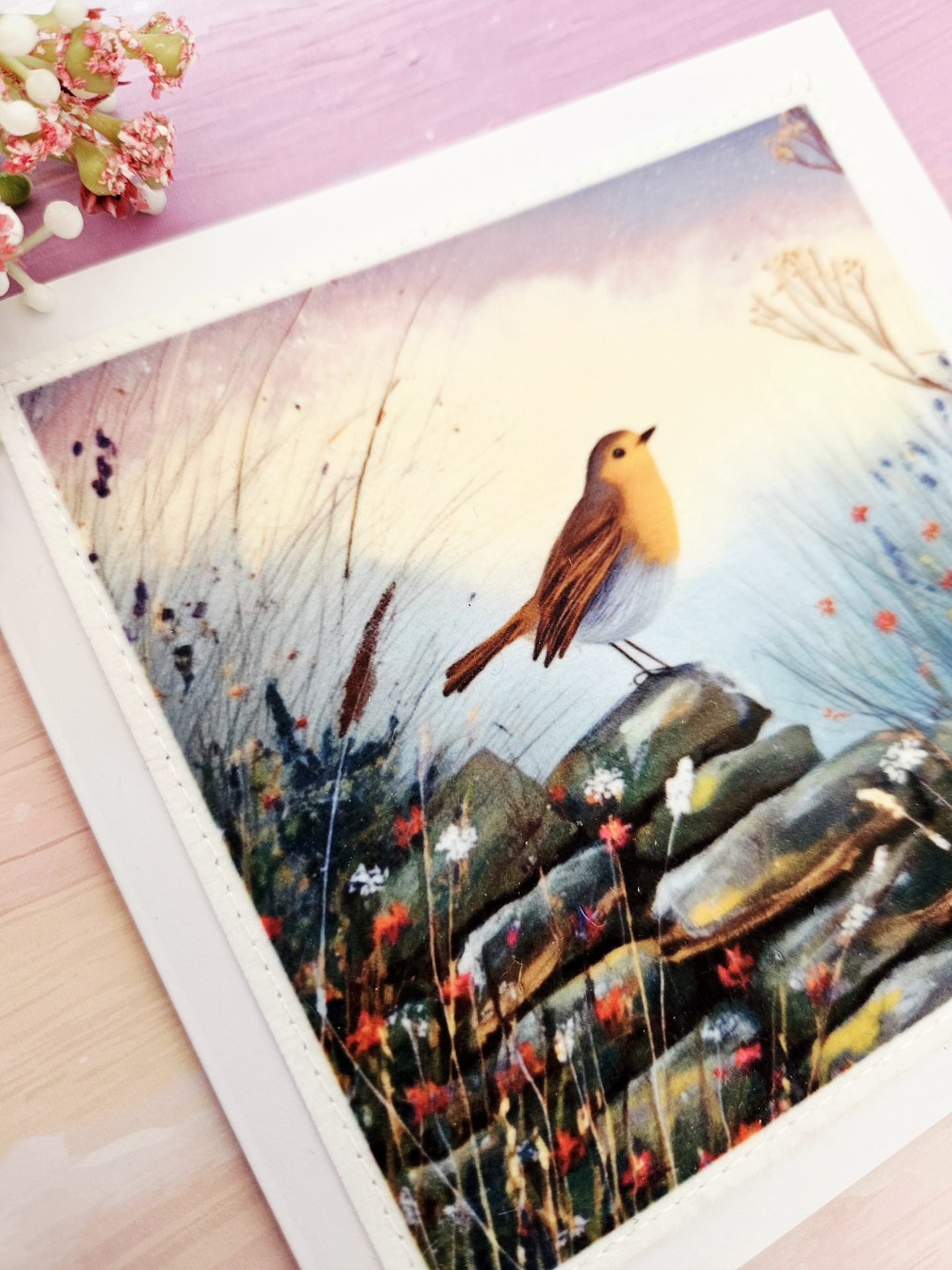 Angled close up view of a handmade fabric print robin greeting card showing the texture of the materials.
