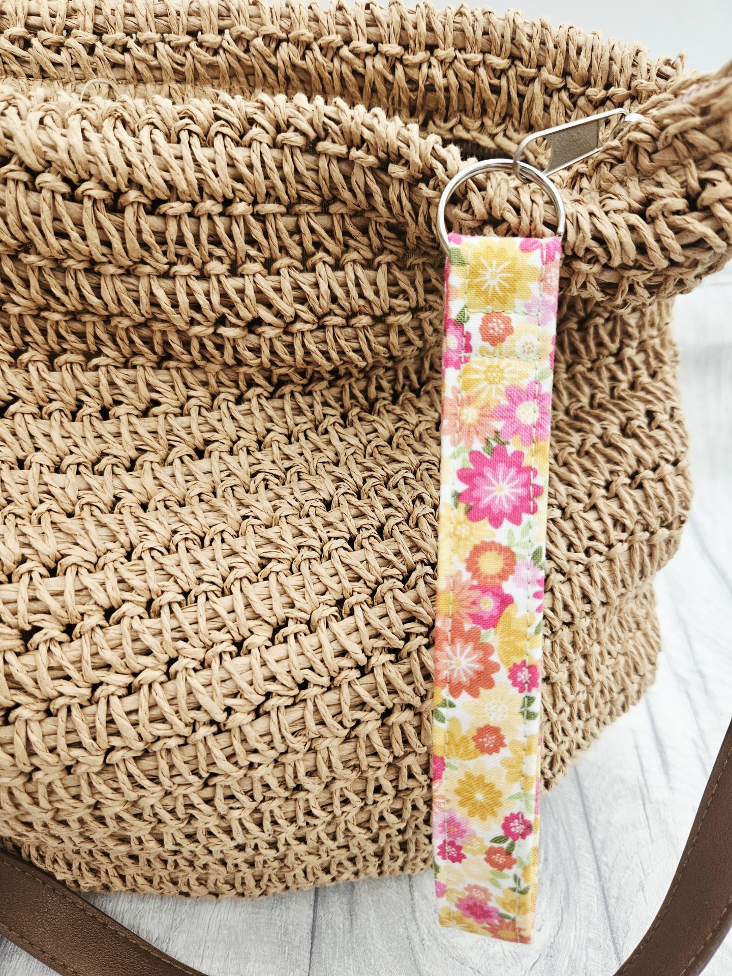 Close-up of a floral fabric wristlet attached to a woven handbag