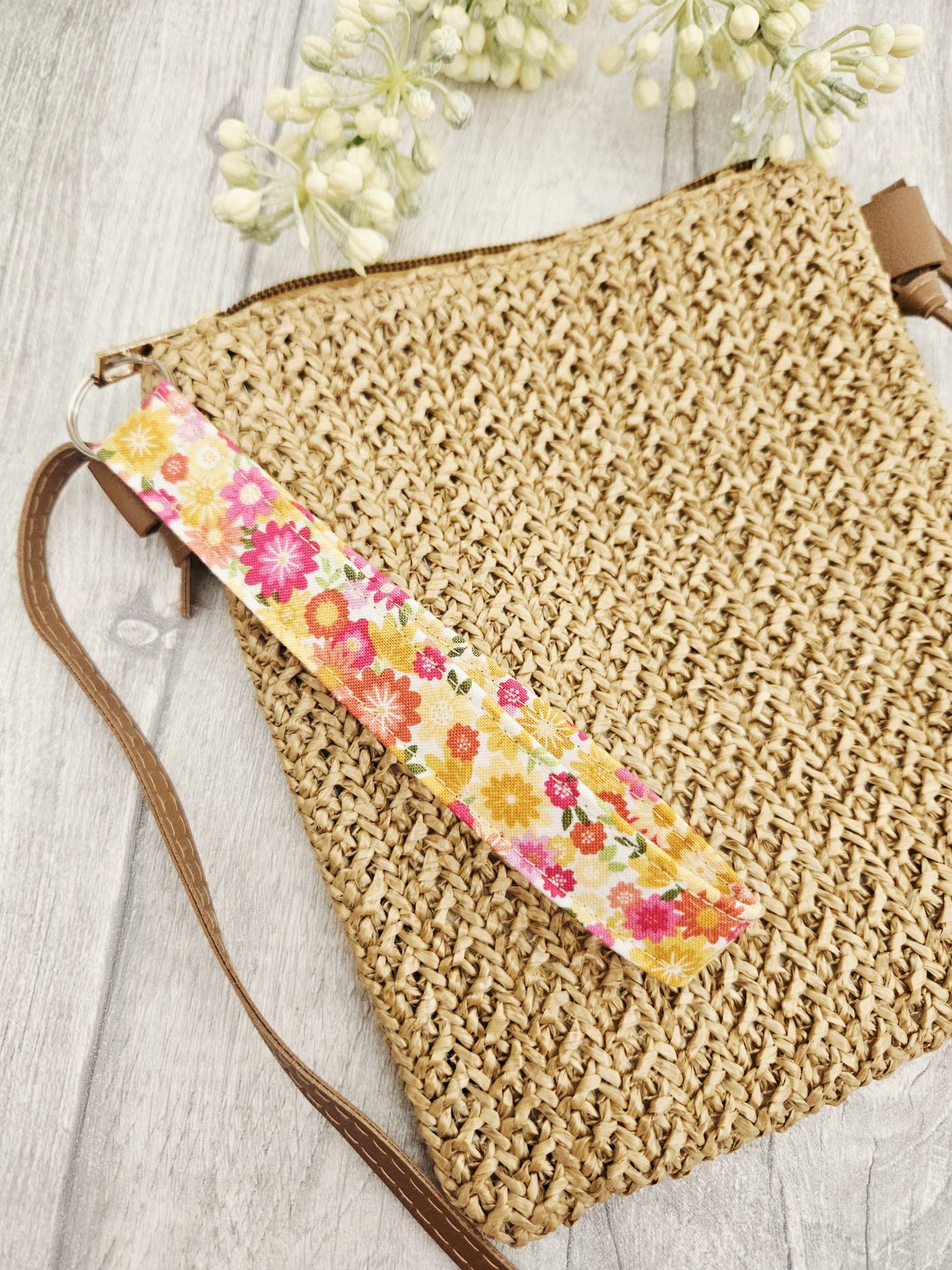 Handmade floral fabric wristlet hanging from the side of a handbag