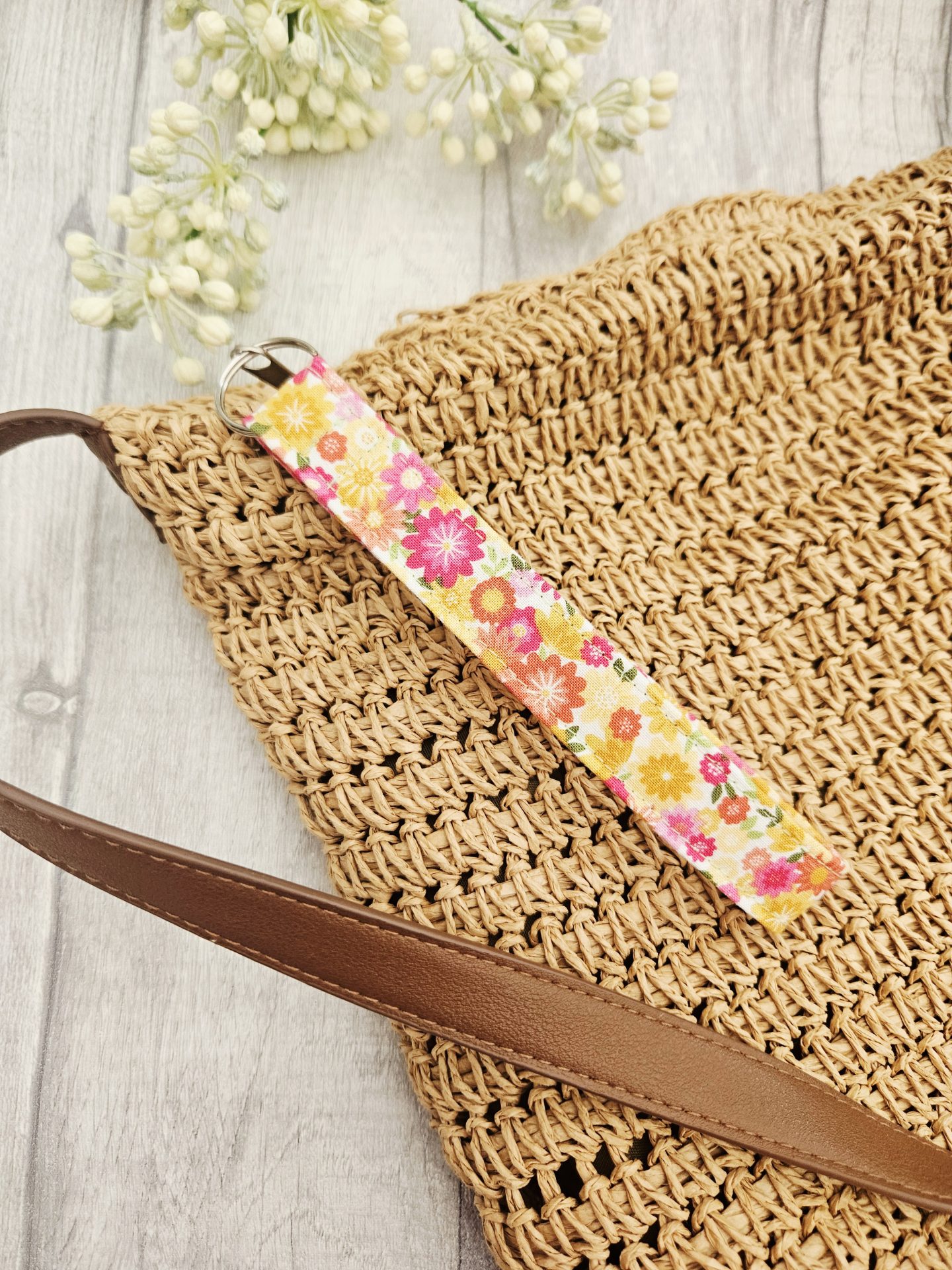 Floral fabric wristlet attached to the front of a woven handbag