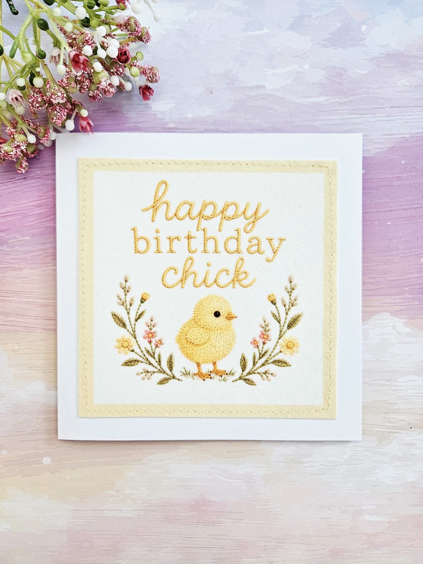 Alt Text: Front view of the handmade birthday chick card featuring an embroidered yellow chick and floral design against a pastel background.
