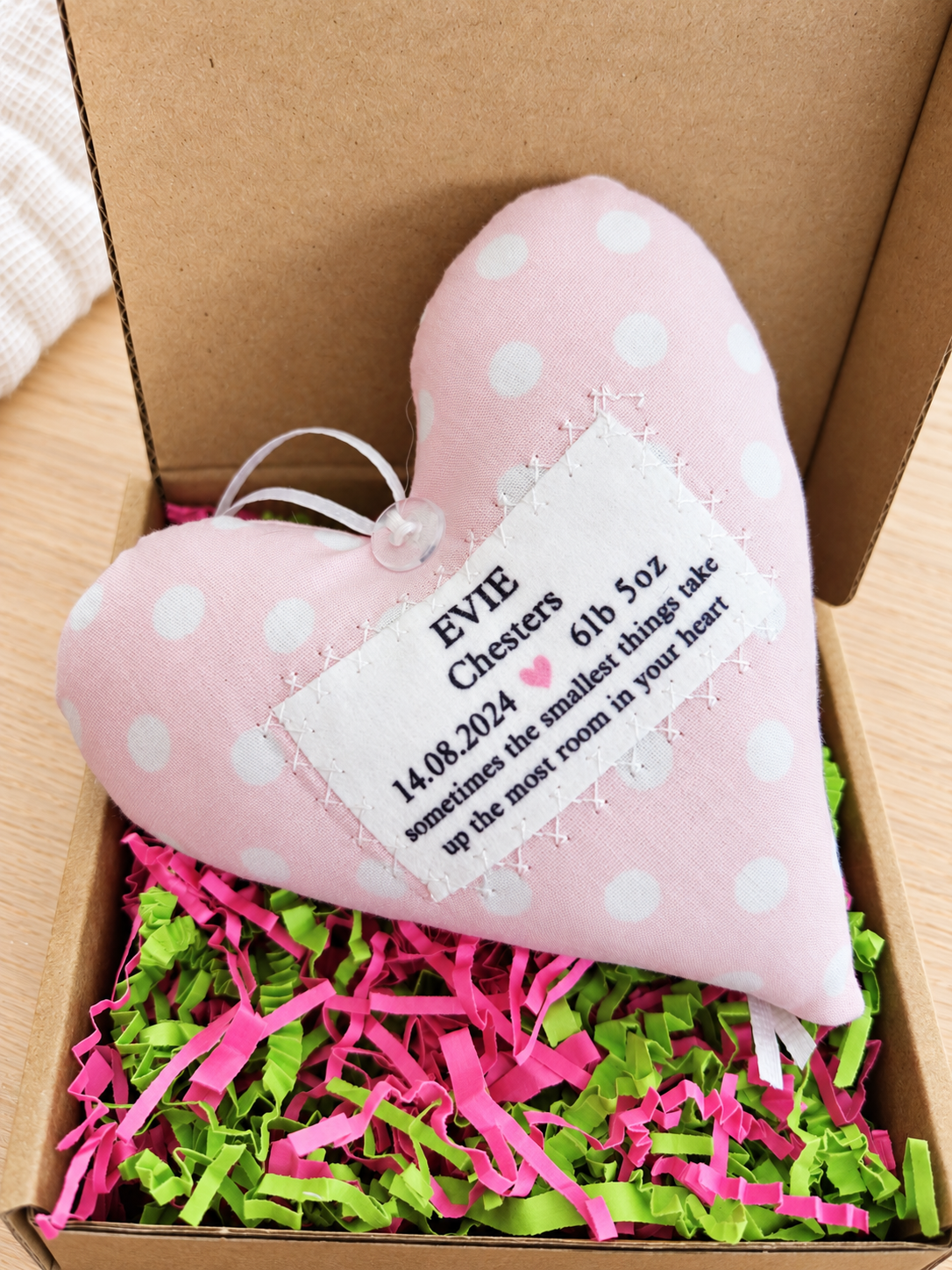 Handmade personalised baby girl fabric heart presented in a kraft gift box with pink and green shredded paper, a special newborn, baby shower or new parents gift.